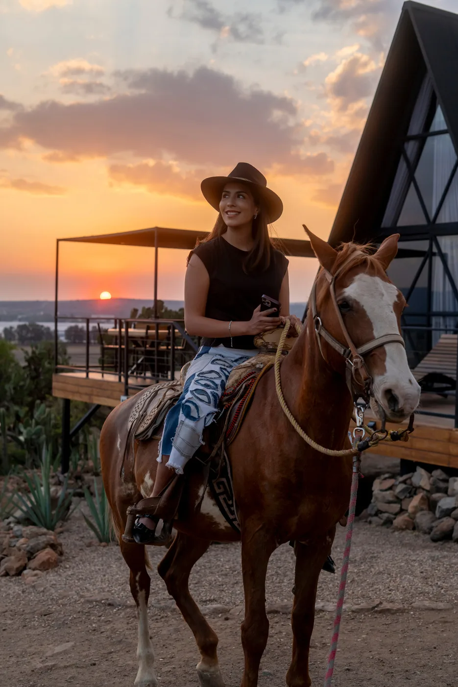 Mujer a caballo frente a las cabañas al atardecer